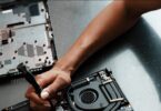 Mano con destornillador reparando el interior de un portátil: placa base y ventilador